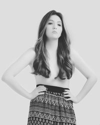 Portrait of young woman standing against white background