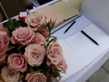 Bouquet of beautiful pink roses with signature book and pen on counter