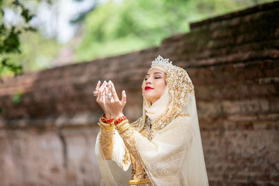 Woman praying against brick wall