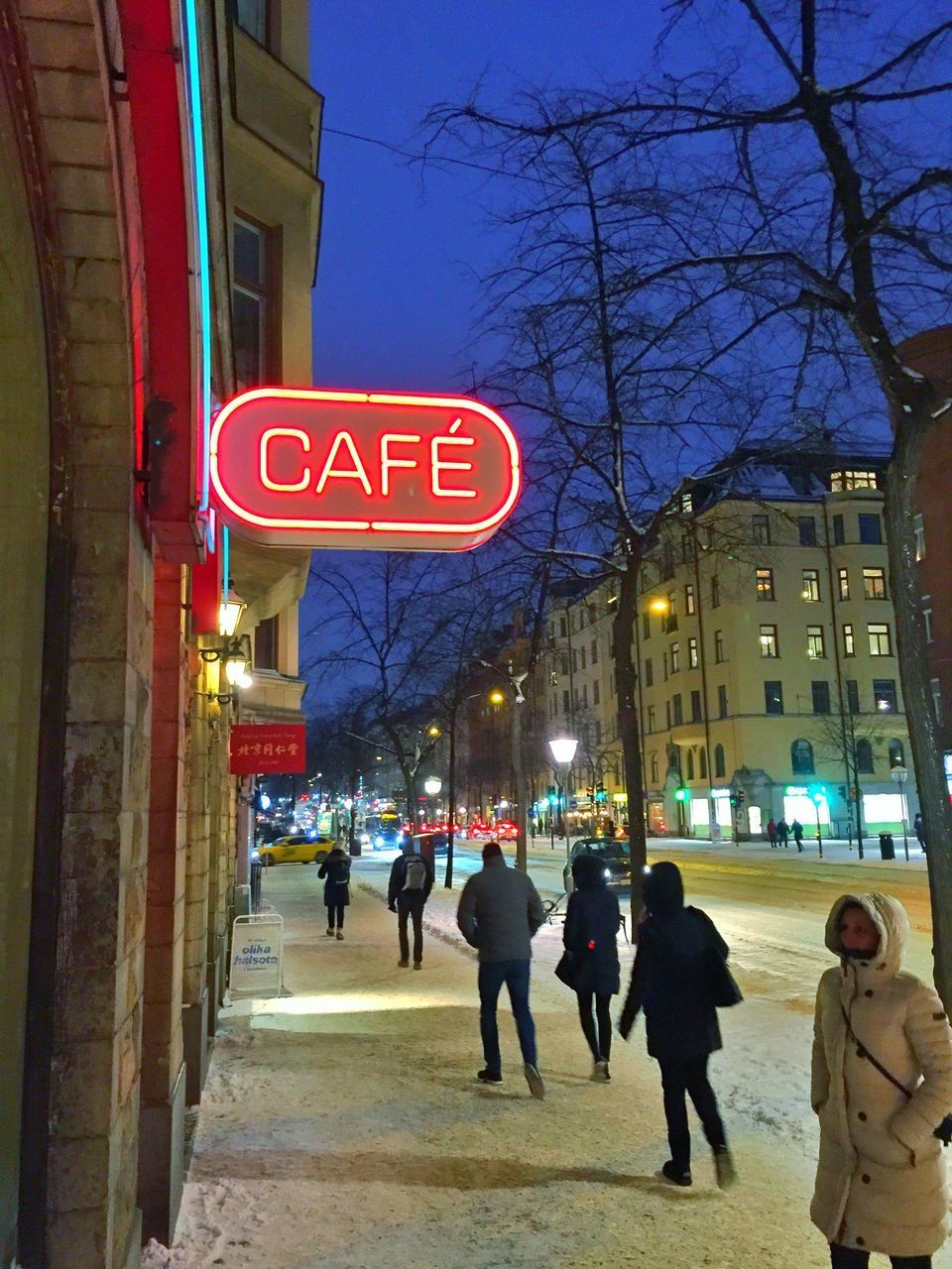 PEOPLE WALKING ON ILLUMINATED CITY STREET