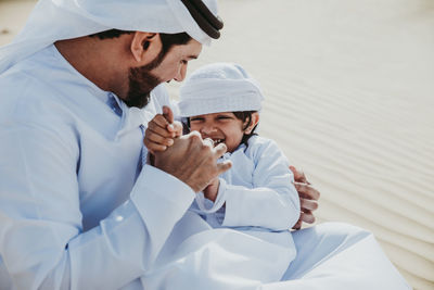 Father and son enjoying while sitting in desert