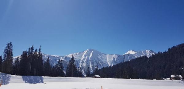 Scenic view of snowcapped mountains against clear blue sky