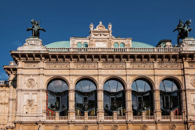 Low angle view of historical opera building against blue sky in vienna 