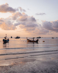 People at beach against sky during sunset