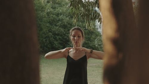 Portrait of young woman standing against trees