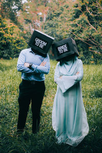 Couple wearing boxes with text while standing on field