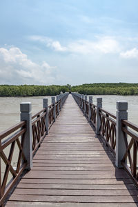View of pier on landscape against cloudy sky