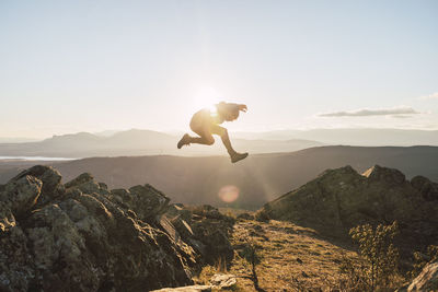 Sportsman jumping on mountain during sunny day