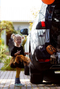 Smiling girl standing by car