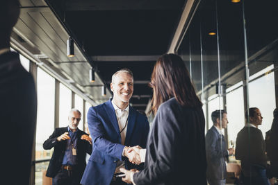 Smiling male entrepreneur shaking hands with businesswoman at workplace