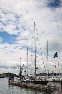 Sailboats moored in harbor against sky