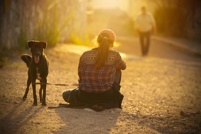 People sitting on street and a guard dog 