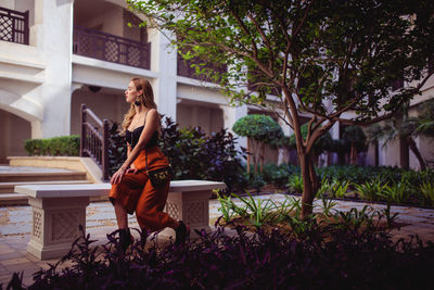 Woman standing by plants against building