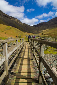 Bridge leading to mountain against blue sky