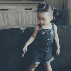 Girl looking away while sitting on sofa at home