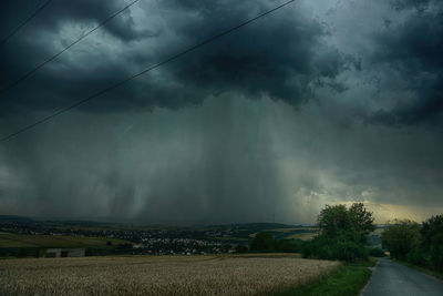 Scenic view of field against storm clouds