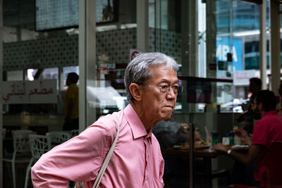 Thoughtful man standing against restaurant in city