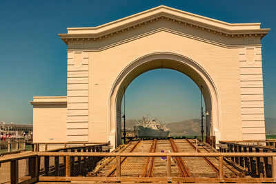 Low angle view of railroad tracks by buildings against clear blue sky