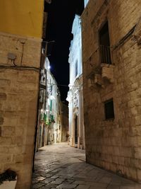 Narrow alley amidst buildings in city at night