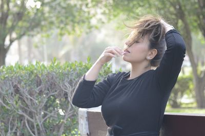 Portrait of beautiful young woman standing against plants