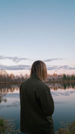 Rear view of woman looking at lake against sky