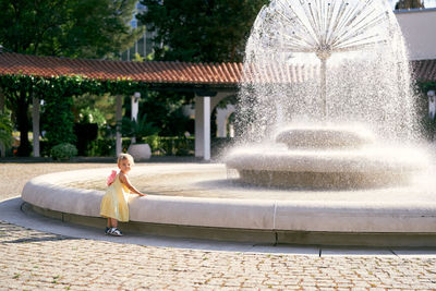 Full length of woman sitting on fountain