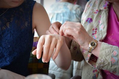 Midsection of woman wearing bracelet to daughter