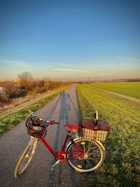 Bicycle on road amidst field against sky