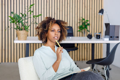 Young woman looking away while sitting at home