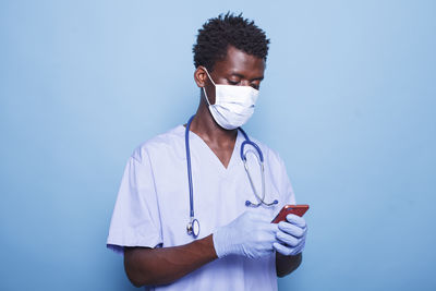 Side view of female doctor holding medicine while standing against blue background