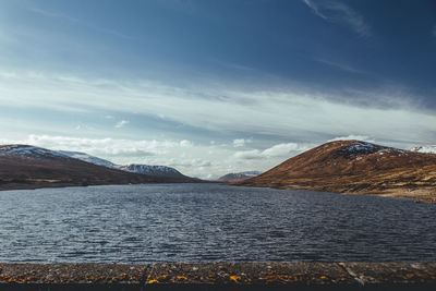 Scenic view of lake by snowcapped mountains against sky