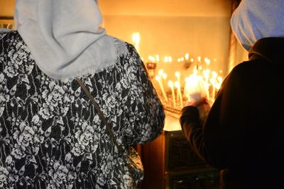 Rear view of man and woman standing against illuminated fire