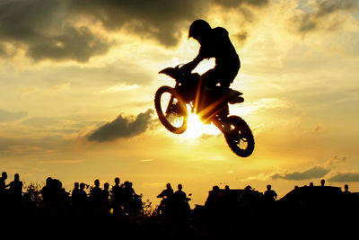 Silhouette man riding bicycle against sky during sunset