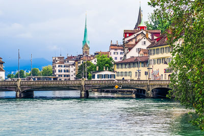 Arch bridge over river against buildings in city