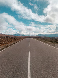 Empty road against cloudy sky