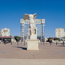 Statue in city against clear blue sky