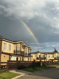 Rainbow over buildings in city against sky