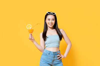 Portrait of a smiling young woman against yellow background