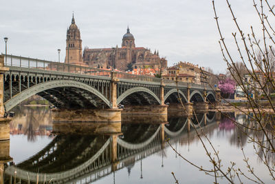 Arch bridge over river against buildings in city