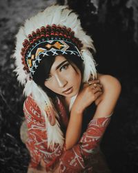 Portrait of young woman standing against black background