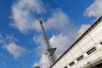 Low angle view of crane and buildings against sky