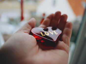 Cropped image of hand holding red heart shape decoration