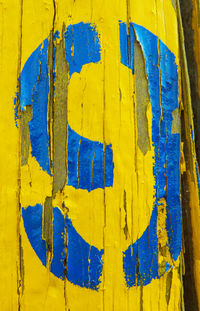 Close-up of damaged paint with number 9 on yellow wood