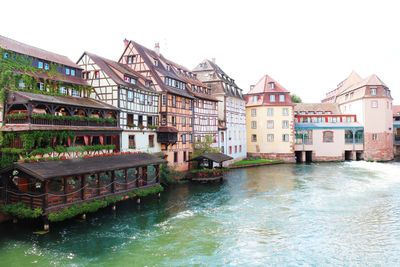 Bridge over river by buildings against clear sky