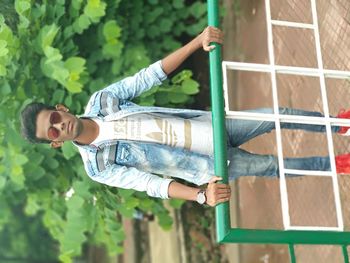 Young man wearing sunglasses standing against plants