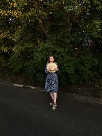 Full length of woman standing on road against trees
