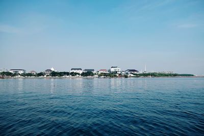 Scenic view of sea by buildings against sky