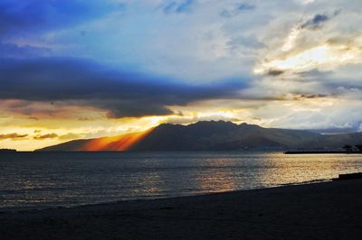 Scenic view of sea against dramatic sky during sunset