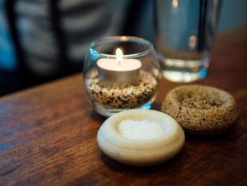 Close-up of tea light candle and seasoning on wooden table