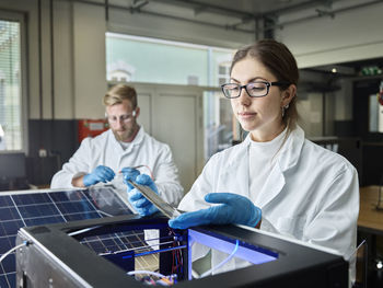 Two technicians working on solar cell in lab